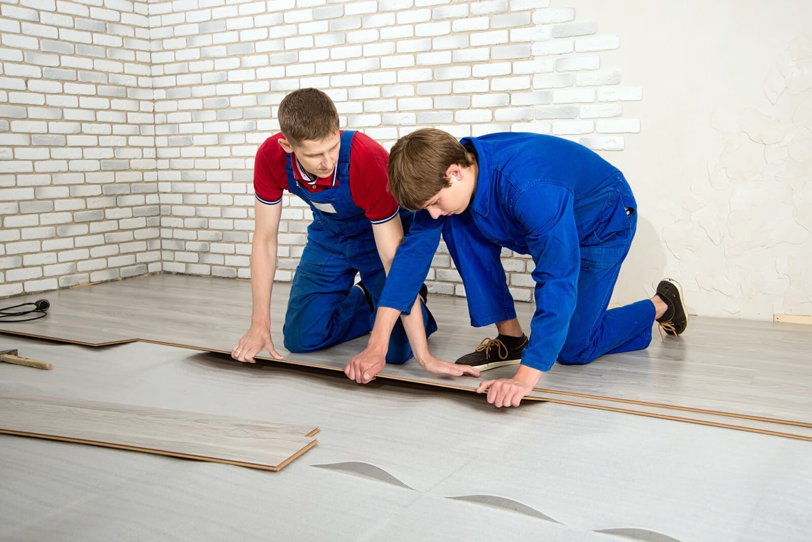 Two workers installing new floor covering during a home project
